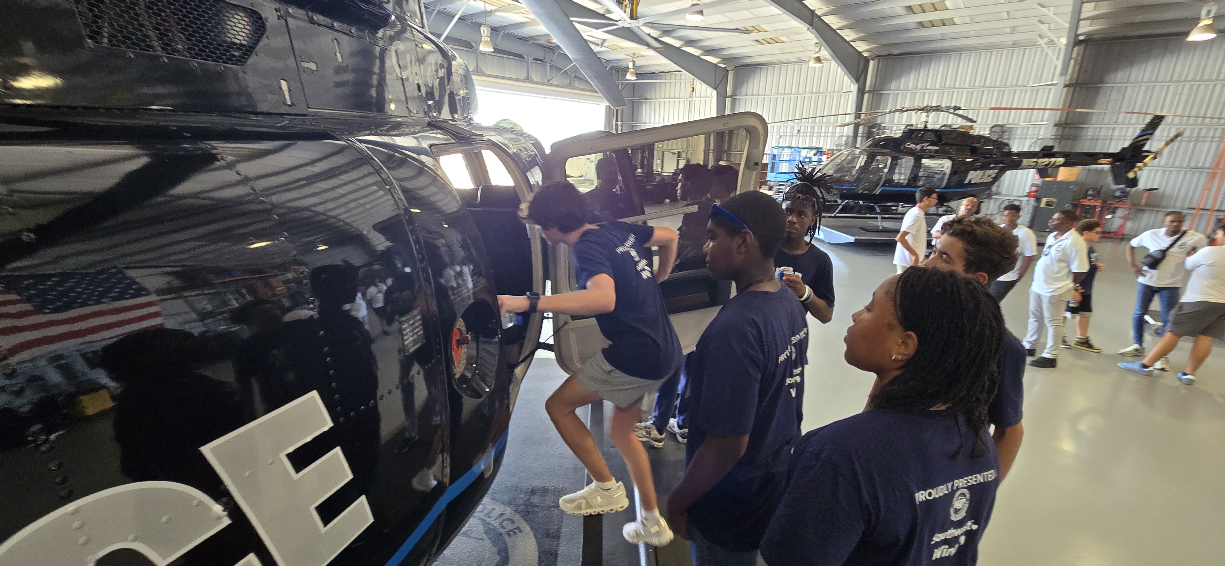 Students exploring a helicopter in an aviation hangar
